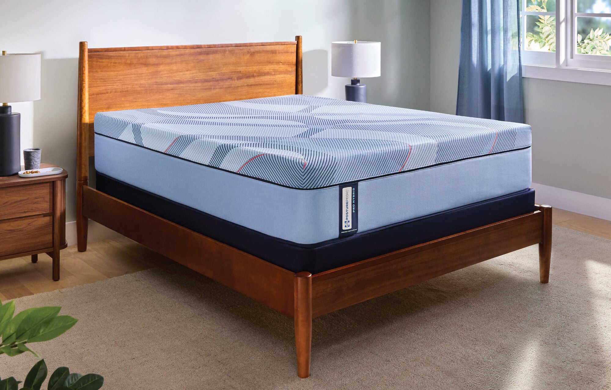 A Sealy Posturepedic Pro mattress on a wooden bed frame beside a nightstand