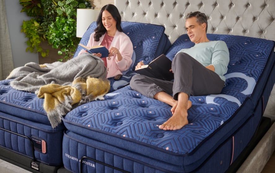 A couple reading on Stearns and Foster mattresses raised on adjustable bases